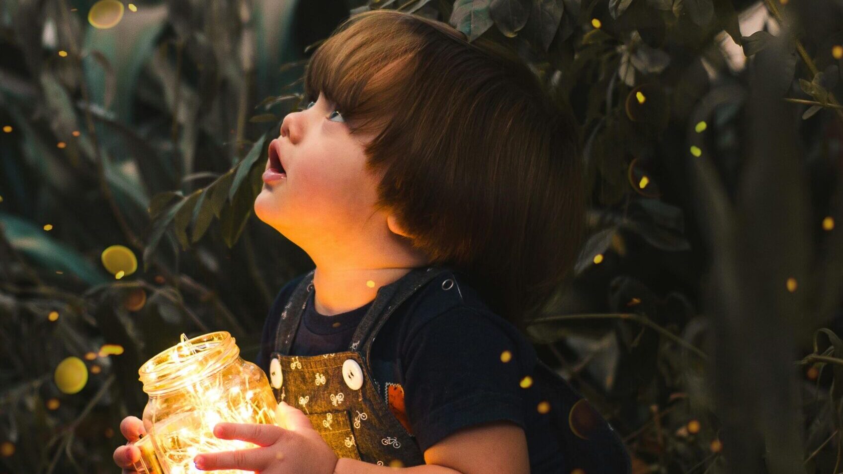 Child Holding Clear Glass Jar With Yellow Light