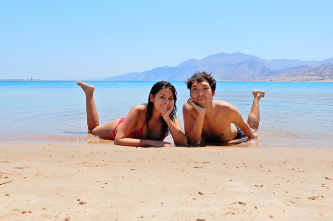 紅海をバックにエジプトのビーチで記念写真を撮る国際結婚５年目のカップル